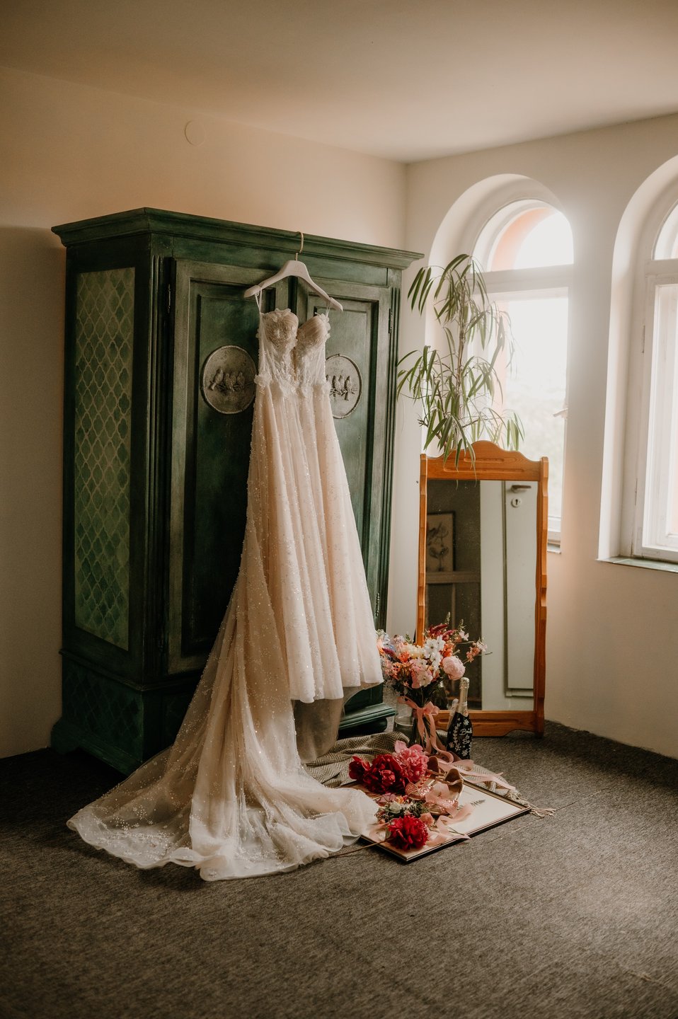 Pokój gościnny: suknia na zielonej szafie, okno łukowe, bukiet (fotograf)